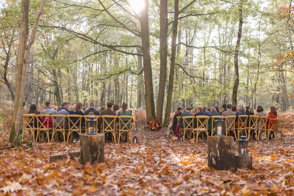 Photographe mariage au domaine de la Roche Couloir pendant la cérémonie laïque en plein cœur de la forêt au Domaine de la Roche Couloir, avec des chaises en bois et une ambiance intime et automnale.