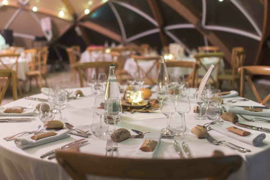 Table de mariage élégamment dressée sous un dôme illuminé, avec des chemins de table en lin et des bougies pour une ambiance chaleureuse.